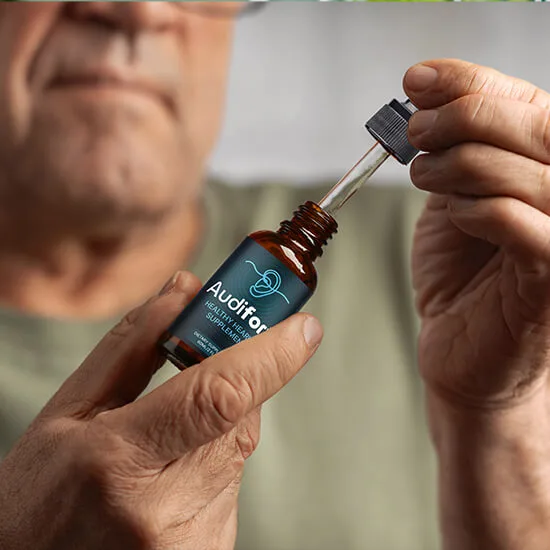 Senior man using Audifort natural hearing support liquid drops for tinnitus relief
